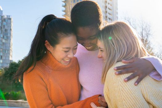 Three female friends affectionately hug each other having fun together laughing happy smiling. Collective lovely embrace concept. High quality photo