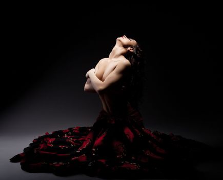Beautiful topless woman posing in flamenko skirt, on black background