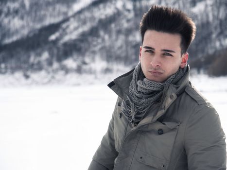 Young attractive man in the mountain in winter with snow around him