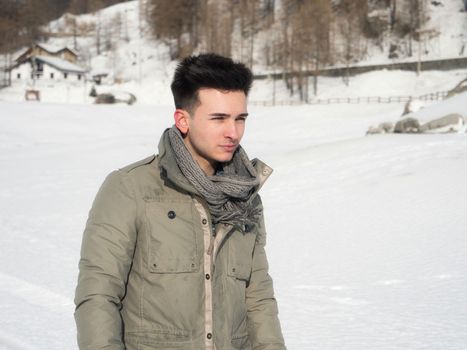 Young attractive man in the mountain in winter with snow around him