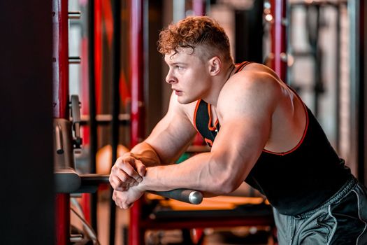 athlete resting in the gym between barbell exercises.