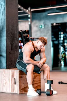 athlete resting in the gym between barbell exercises.
