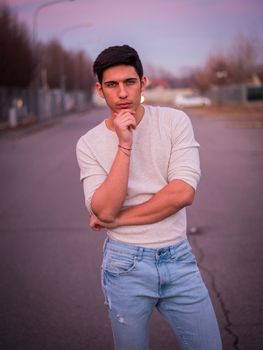 Handsome young man in white sweater outdoor in street, looking at camera