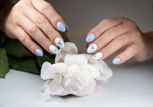 girl with a beautiful white blue manicure with a bouquet of delicate peonies, . High quality photo