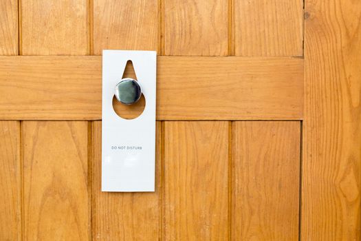 please do not disturb sign on Closed wooden door of hotel room.