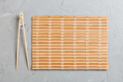 two sushi training sticks with empty bamboo mat or wood plate on stone Background Top view with copy stace.