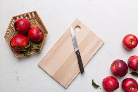 Fresh red apples with green leaves on table. cutting board with knife. Top view.