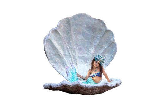 A cute little girl in a mermaid costume sits in a large sea shell, isolated, on a white background