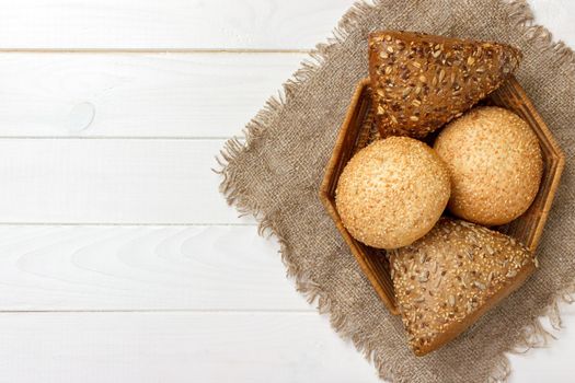 Bread rolls in the basket on rustic wooden background.