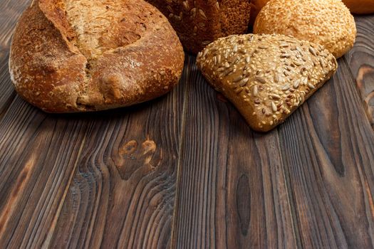 Assortment of baked bread on dark wooden background. Bakery and grocery food store concept. Flat lay with space for text.