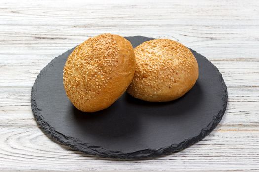 Delicious fresh buns with sesame seeds on a slate board. Top view.