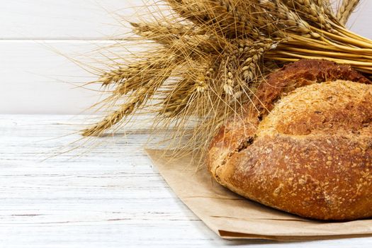 Rustic bread and wheat on an old vintage planked wood table. free text space.