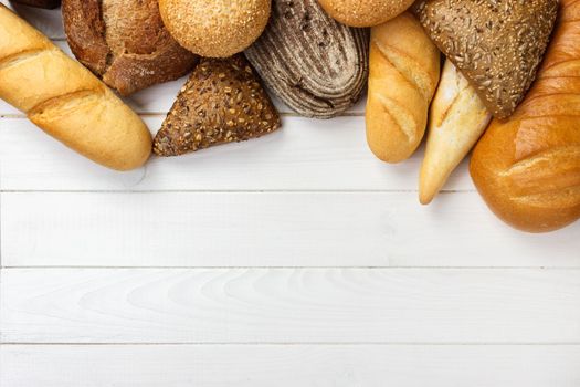 Assortment of baked bread on wooden table background. top view with copy space.