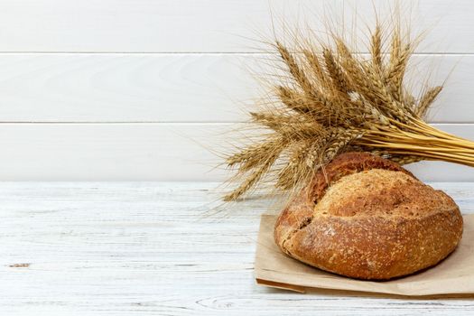 Homemade loaf of wheat bread baked on wooden background.