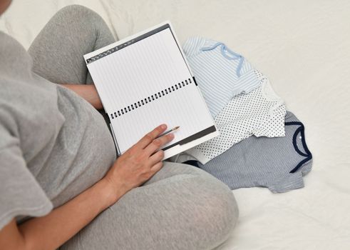 Pregnant woman makes the notes in notebook
