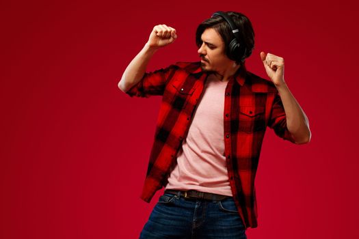 Handsome european man in yellow outfit smiling and dancing in excellent mood on blue background. Slow motion.