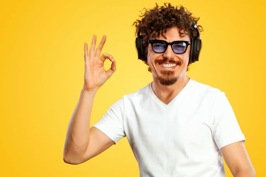 Portrait of a happy bearded man pointing fingers up at copyspace isolated over yellow background