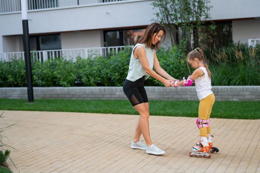 Mother helps daughter learn to roller skate
