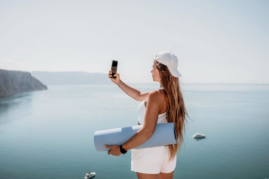 Young woman with black hair, fitness instructor in pink sports leggings and tops, doing pilates on yoga mat with magic pilates ring by the sea on the beach. Female fitness daily yoga concept