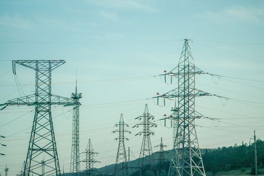 Silhouette High voltage electric tower on sunset time, distribution electric substation with power lines and transformers.
