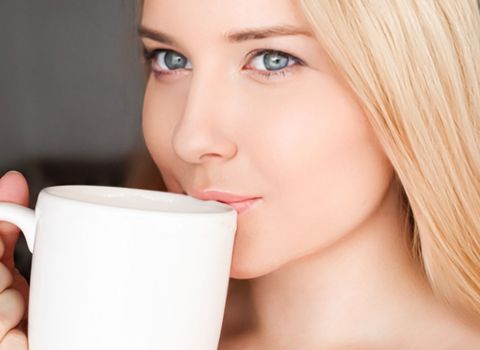 Beautiful blonde woman having a cup of tea in the morning at home.