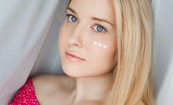 Beautiful woman with skincare cream on her face.