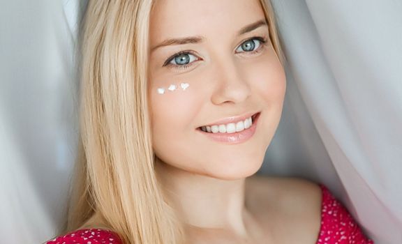 Beautiful woman with skincare cream on her face.