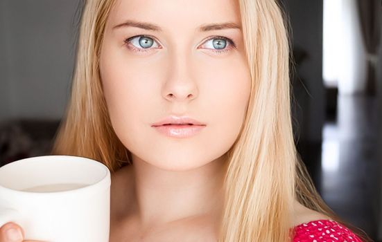 Beautiful blonde woman having a cup of tea in the morning at home.