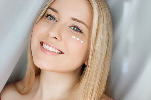 Beautiful woman with skincare cream on her face.