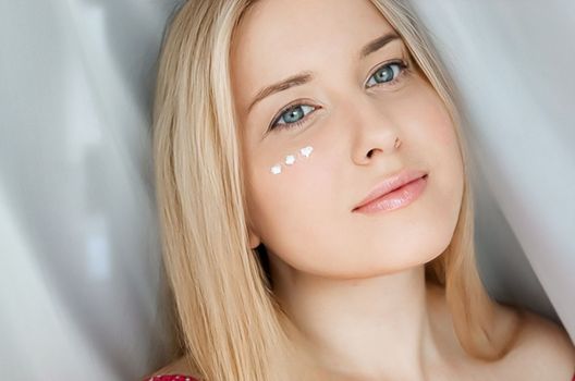 Beautiful woman with skincare cream on her face.