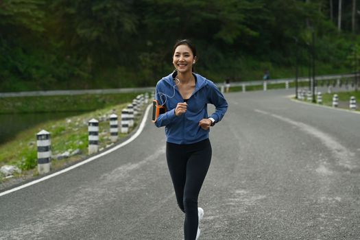 Active sporty woman jogging in the park at the morning. Healthy lifestyle, workout and wellness concept.