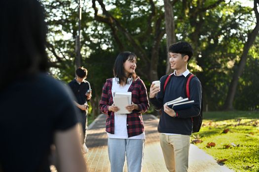 Two asian college students having break after classes and twirling in campus. Youth lifestyle and friendship concept.