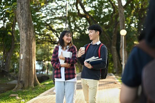 Shot of two asian student talking to each other while going to lecture at the university.