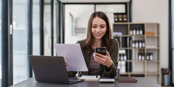 Smiling asian business woman with smartphone in office. Woman in casual at office.