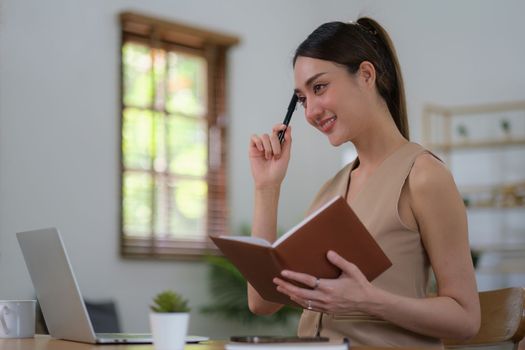 Portrait of Asian woman reading a book beside the window after get up in morning. Morning lifestyle concept.