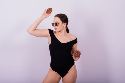 Close up shot of nude woman's body with chocolate covered donuts