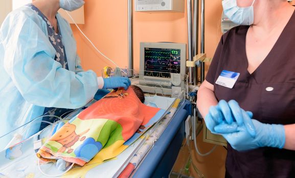 A young nurse caring for a newborn in a hospital in the intensive care unit.