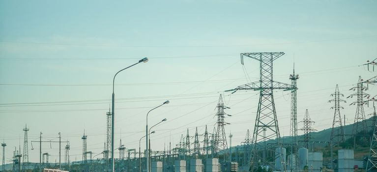 Silhouette High voltage electric tower on sunset time, distribution electric substation with power lines and transformers.