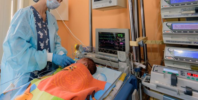 A young nurse caring for a newborn in a hospital in the intensive care unit.