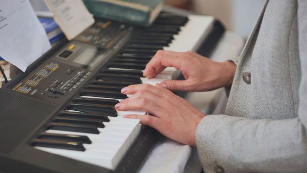 The woman plays the synthesizer. Close-up of her hands
