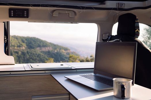 interior table of a camper van with a laptop and a mug, concept of freedom and digital nomad lifestyle