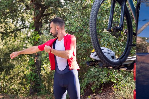 young man dressing up with cycling clothes next to his van to go training with his mountain bike, concept of freedom and sport in nature