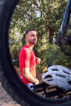 young man dressing up with cycling clothes next to his mountain bike to go training, concept of freedom and sport in nature