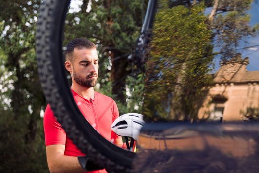 young man getting ready in cycling clothes next to his van to go training with his mountain bike, concept of freedom and sport in nature