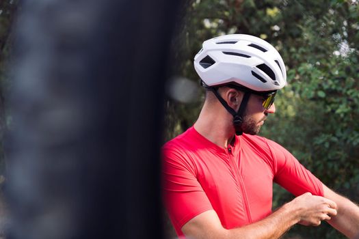 young man dressing up with cycling clothes next to his mountain bike to go training, concept of freedom and sport in nature