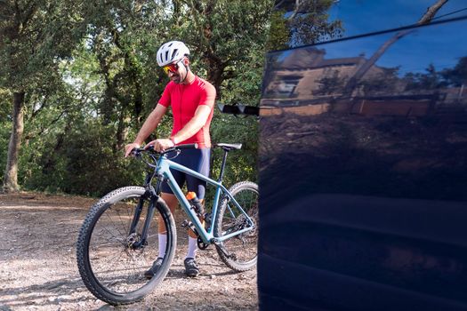 young man in cycling clothes loading the route on his mountain bike navigator to go for a training ride, concept of freedom and sport in nature