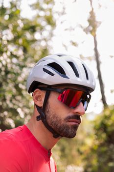 portrait of a young man wearing a helmet and cycling goggles in the middle of the forest, concept of freedom and sport in nature, copy space for text