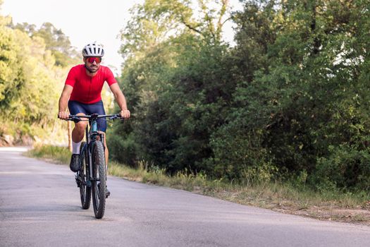 young cyclist riding relaxed with his mountain bike on a forest road, concept of freedom and sport in nature