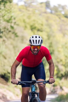 young cyclist training hard with his mountain bike on a forest road, concept of freedom and sport in nature, copy space for text