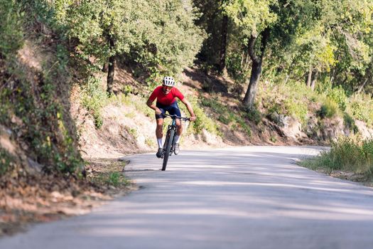 young cyclist training hard with his mountain bike on a forest road, concept of freedom and sport in nature, copy space for text